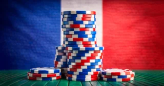 Pile di fiches rosse, bianche e blu su uno sfondo della bandiera francese, simbolo di un casinò online.